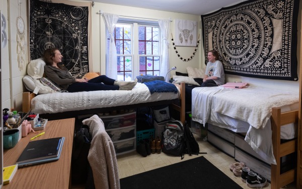 Female students talking on beds in fully decorated dorm room