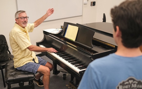 Voice coach at piano giving lessons to a student