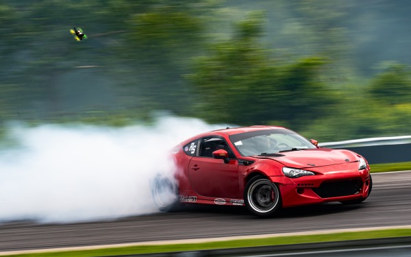 Car speeding down the road with white smoke trailing behind