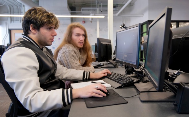 Two male students working on computers in a classroom