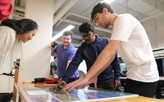 Engineering students at competition looking at poster on table