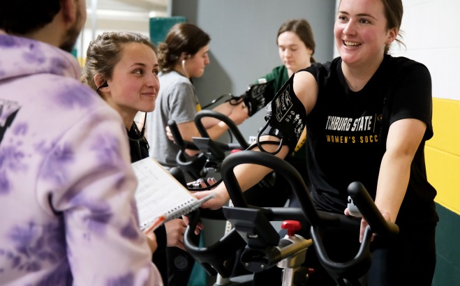 Students taking blood pressure while student rides exercise bike