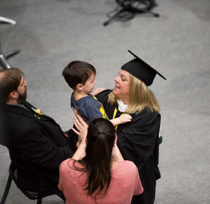 Graduate smiling at child surrounded by family