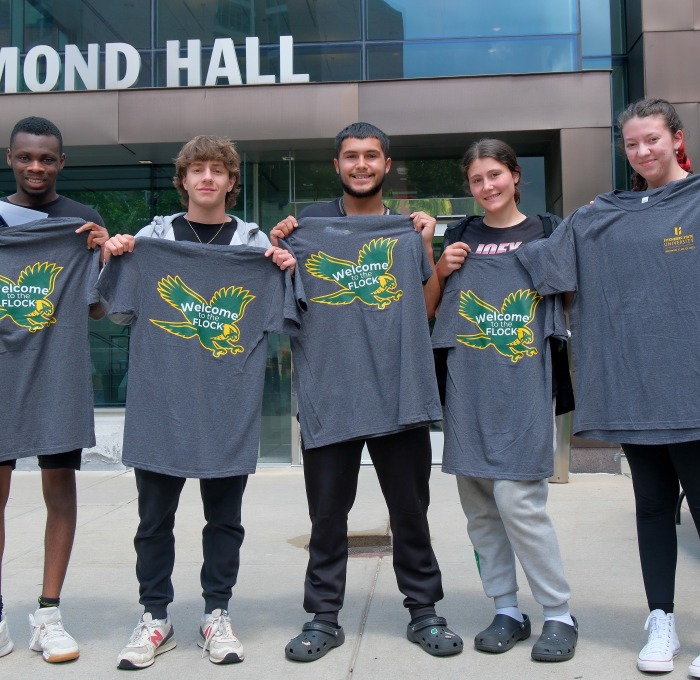 Students holding welcome to the flock tshirts in front of Hammond Hall