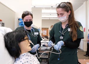 Nursing students in lab pushing a line into patients nose