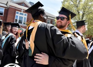 Male students smiling and embracing at commencement on quad