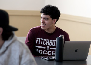 Smiling FHS student with laptop in classroom.