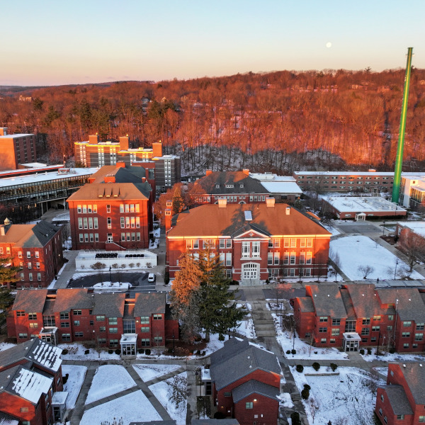 Aerial quad at sunrise in winter with snow on ground and moon in sky