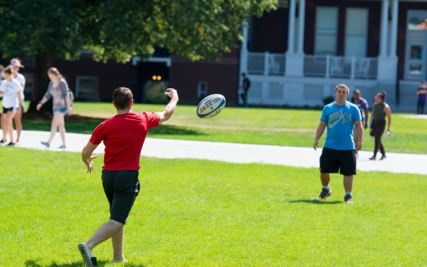studnets toss a football on the quad