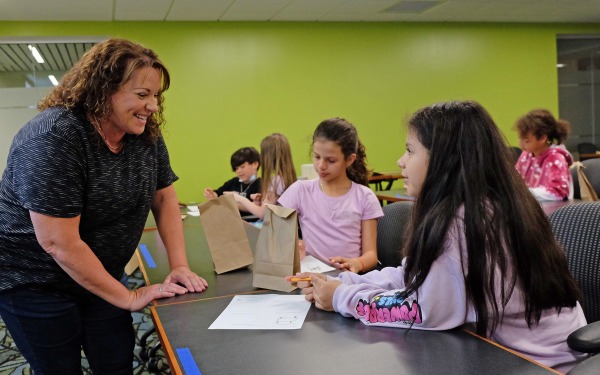 Teacher smiling at two female students in McKay classroom