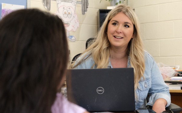 Elementary school counselor talking to student behind laptop