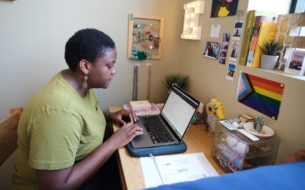 Evie in her simonds dorm on her laptop at desk