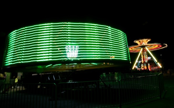 Spinning carnival rides with green and gold lights