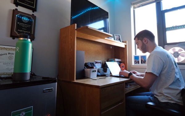 Joe in townhouse dorm at desk on laptop