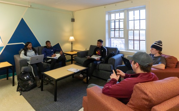 Students in common space in dorm talking and working