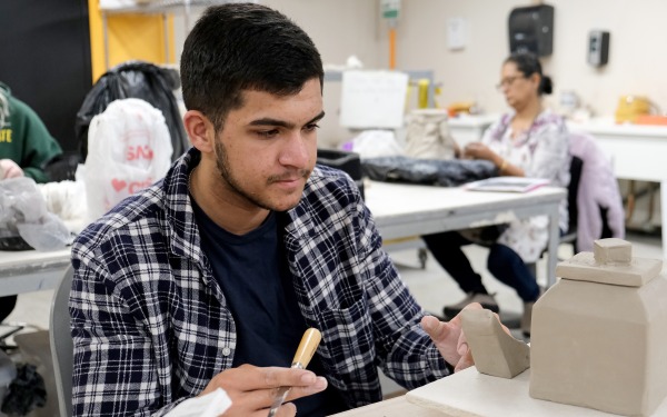 Male student in ceramics class working on pottery