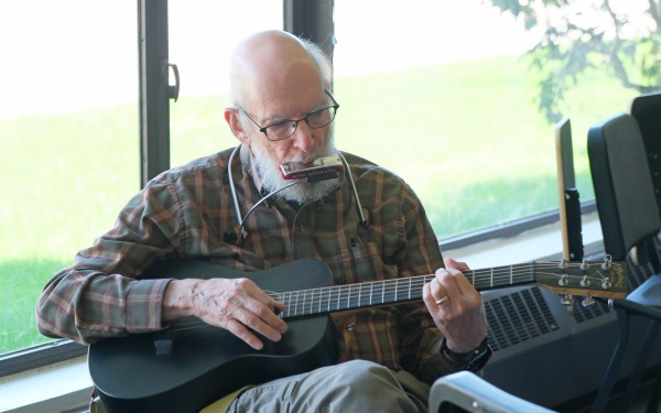 Older man playing guitar and harmonica