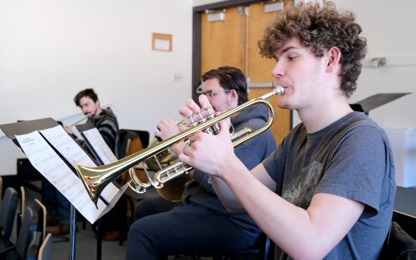 Male students playing wind instruments in music room