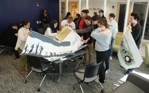 students looking thru posters stacked on table in classroom