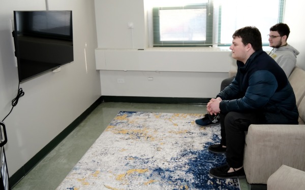Two male students sitting on couch facing tv in common area in Herlihy