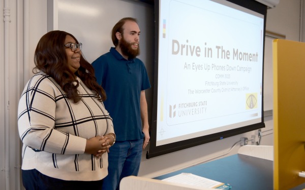 Students present drive save campaign in front of white screen presenting