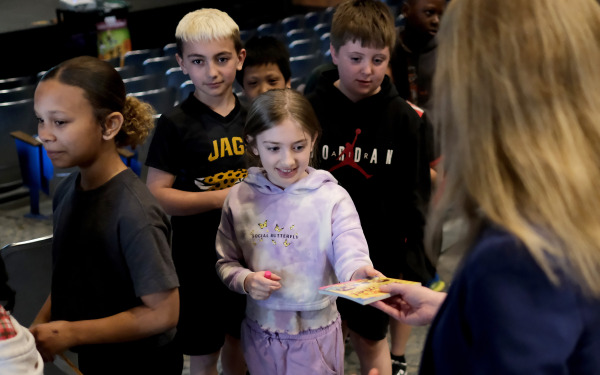 Group of McKay students receiving books from teacher.