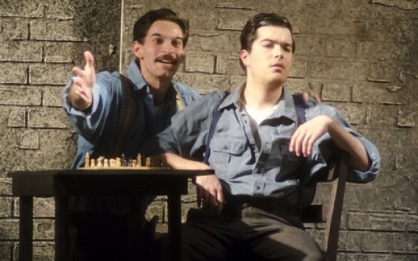Two actors at a chess table in "(Sacco-Vanzetti): Vince, Al, & Teddy"
