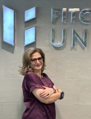 Mojdeh Bayat, Dean of Education in front of shield on the wall