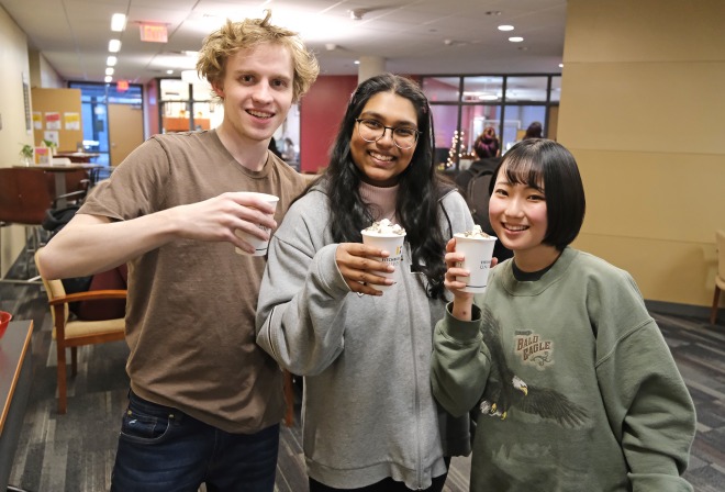 One male and two female students with hot chocolate on 3rd floor of Hammond