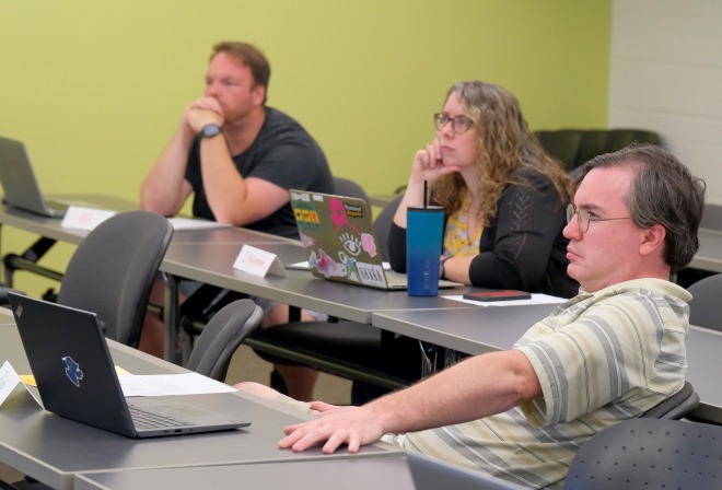 Two male and one female AP student listening intently in a classroom