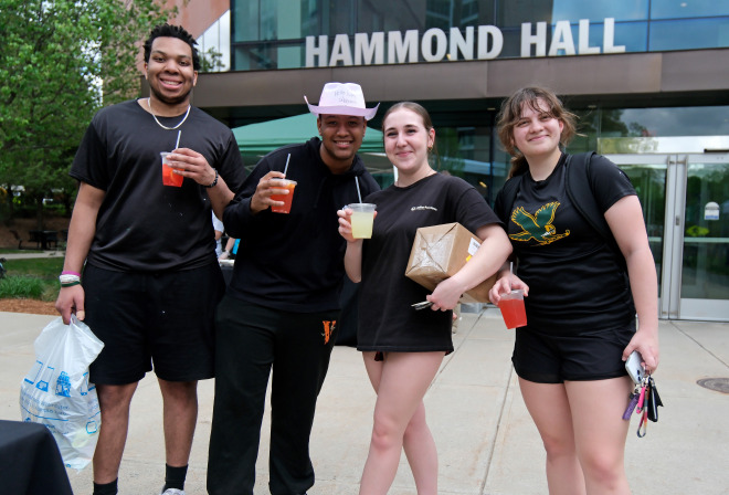 Male and female students in front of Hammond Hall with free drinks.