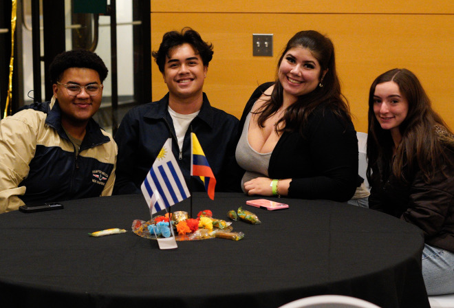 Diverse group of students at table at Noche event in main lounge.