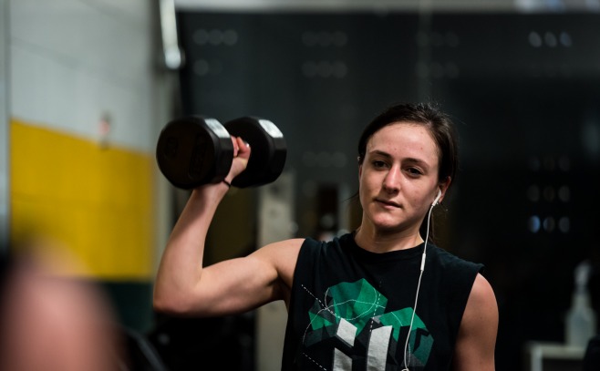 a female student lifts weights in the rec center