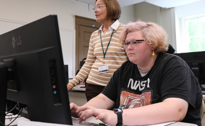 Upward Bound student at computer with teacher in background