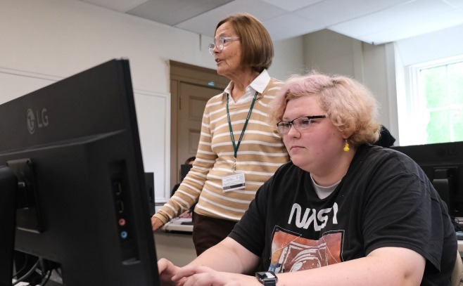 Upward Bound student at computer with teacher in background