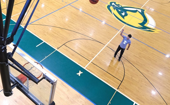 Student shooting baskets in gym from above