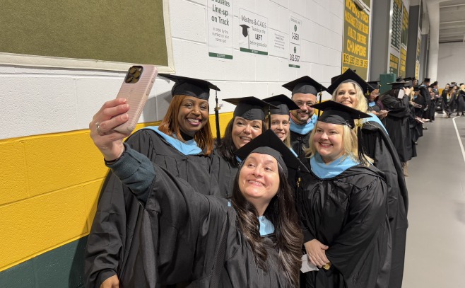 Group of grad students taking a selfie on the track in the gym