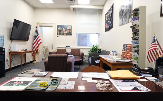 Interior photo of the veteran's lounge with desks, tables, chairs and military posters