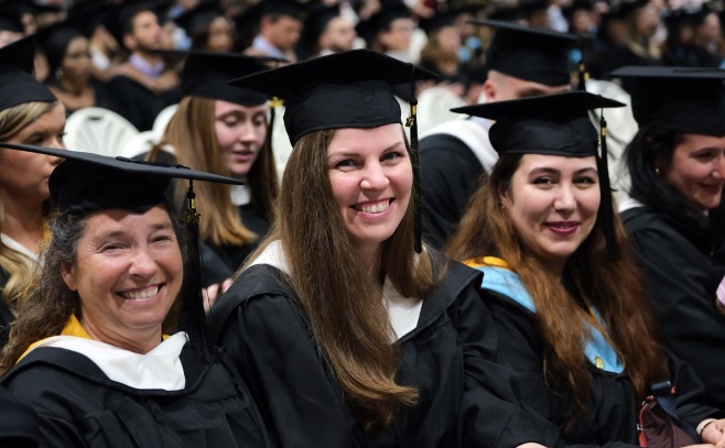 Group of smiling grad students sitting during ceremony