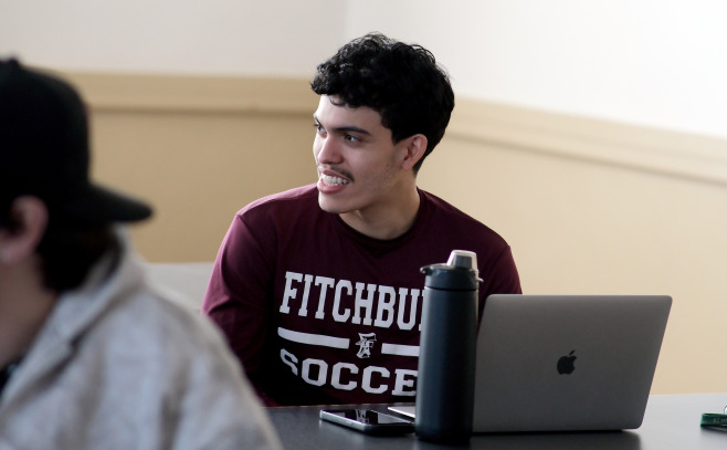 Smiling FHS student with laptop in classroom.