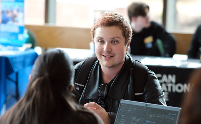 Student sitting at the Graduate Fair in Hammond Hall Main Lounge.