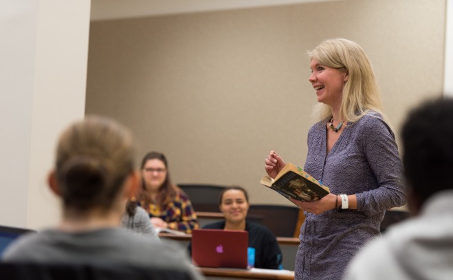 Professor Katy Covino holds book during lecture 