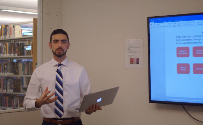 Business student with computer at white board giving presentation 