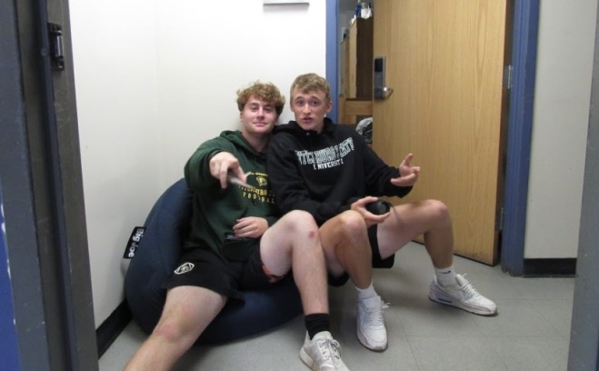 Two male students sitting in a bean bag in hallway of a resident hall