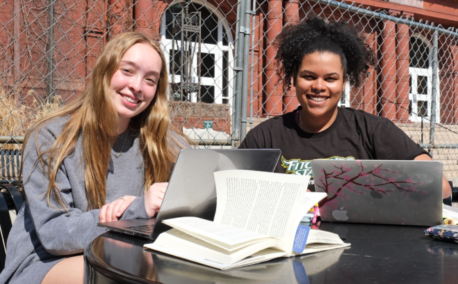 Students with laptops and books smiling near Thompson