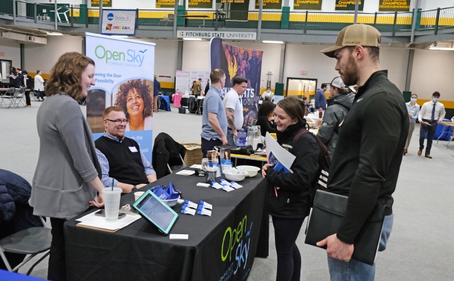 Male and female student talking to employers at booth at career fair in rec center