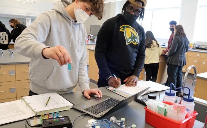 Two male students testing chemicals in lab