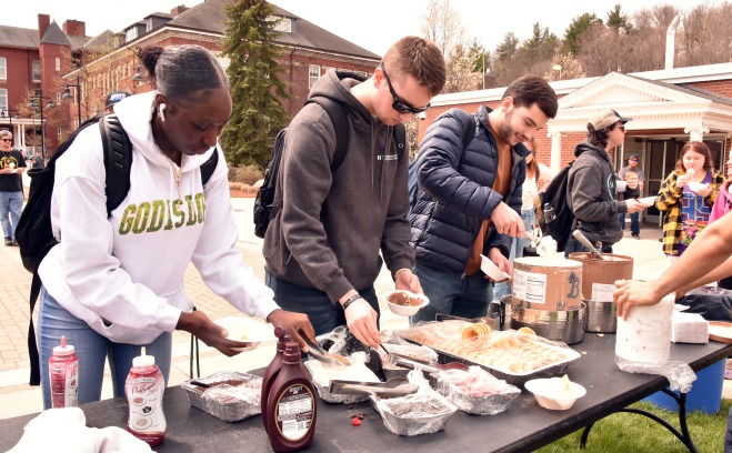 Male and female students making ice cream sundaes on the quad