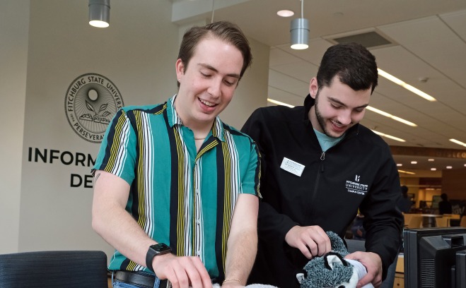 Male students at information desk working and making stuffed animals