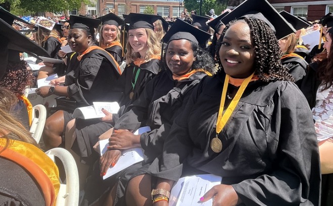 Seated graduates smiling at commencement